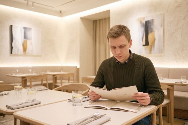 Elección de un platillo en el menú del restaurante con ansiedad Hombre revisando el menú en un restaurante para elegir un platillo seguro.