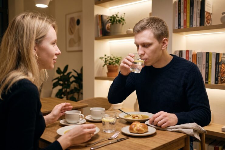 Apoyo de seres queridos y ambiente tranquilo en la mesa Hombre bebiendo agua mientras conversa con una mujer durante una cena en un café acogedor.