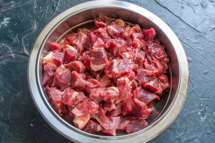 Preparación de la carne Trozos de carne cruda de res cortada en un tazón de acero inoxidable