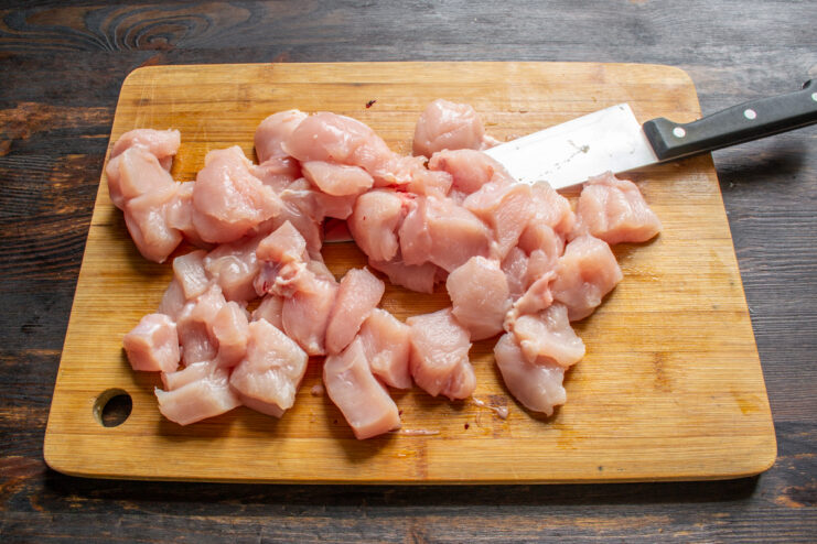 Preparación del filete de pollo Filete de pollo cortado en cubos sobre una tabla de madera