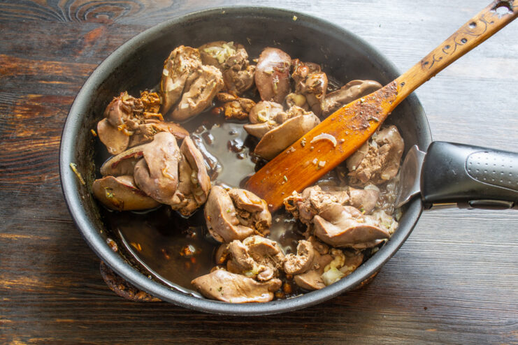 Vino tinto seco vertiéndose sobre el hígado en la sartén
