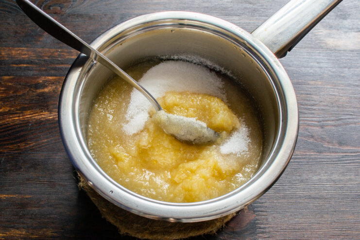 Adición de azúcar al puré Agregando azúcar al puré de manzana dentro de una cacerola.