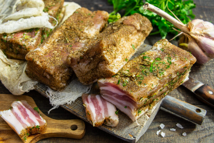 Panceta de cerdo curada lista servida con ajo y hierbas frescas