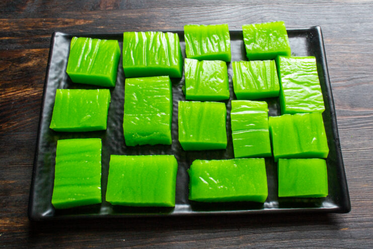 Gomitas de manzana terminadas Cubitos de dulce de manzana verde servidos en un plato negro.
