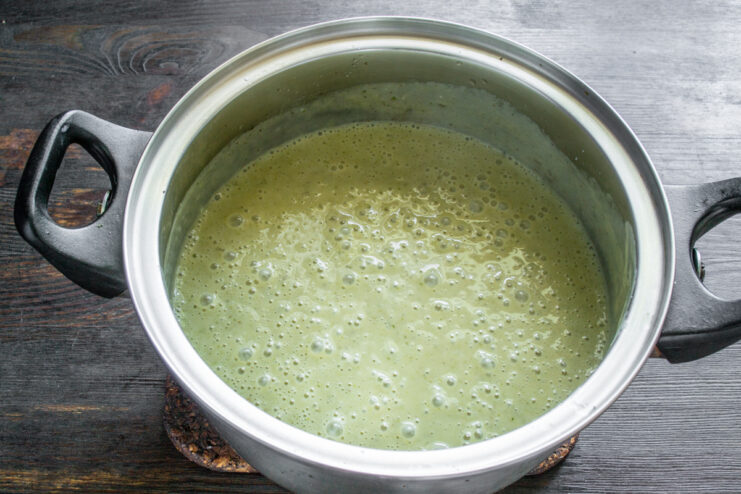 Calentamiento de la sopa terminada Crema de zucchini terminada y caliente en una olla de metal.