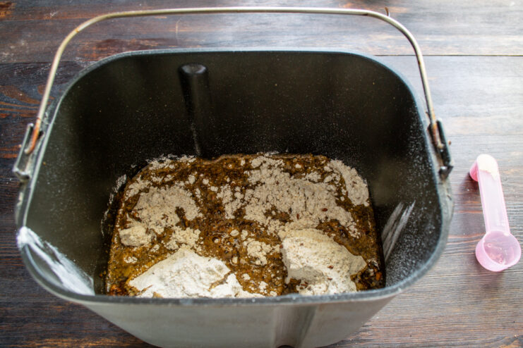 Carga en la panificadora Ingredientes para el pan de linaza en el molde de la panificadora