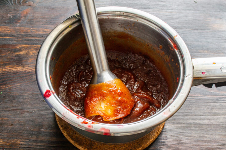 Licuado de la salsa Triturando la salsa de dátiles con una licuadora de inmersión dentro de una olla