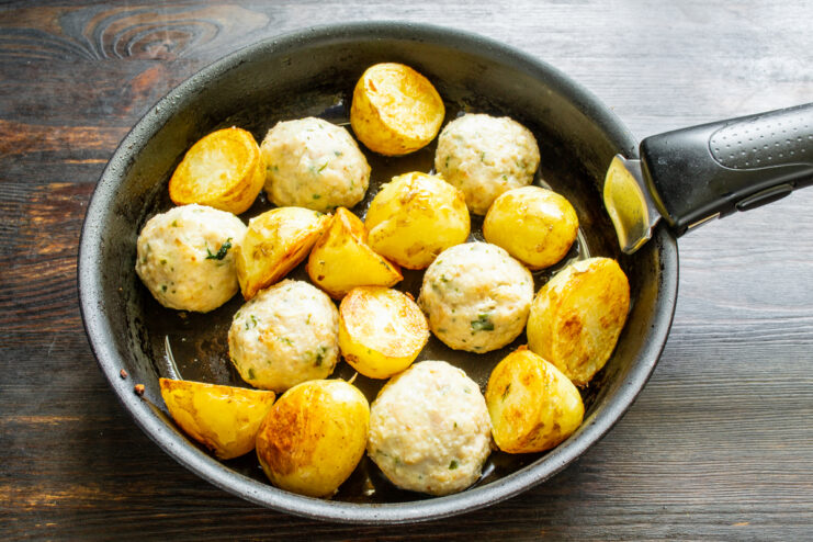 Salteado de papas y albóndigas Cocinando papas doradas y albóndigas juntas en una sartén