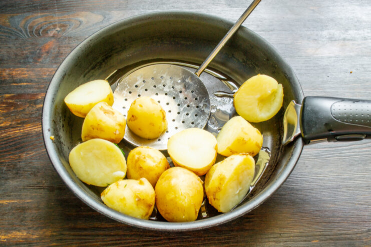 Salteado de las papas Papas cocidas dorándose en una sartén con mantequilla y aceite