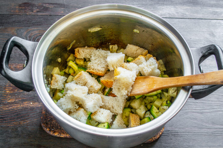 Adición de los cubos de pan Cubos de pan blanco incorporados a la mezcla de verduras en la olla.