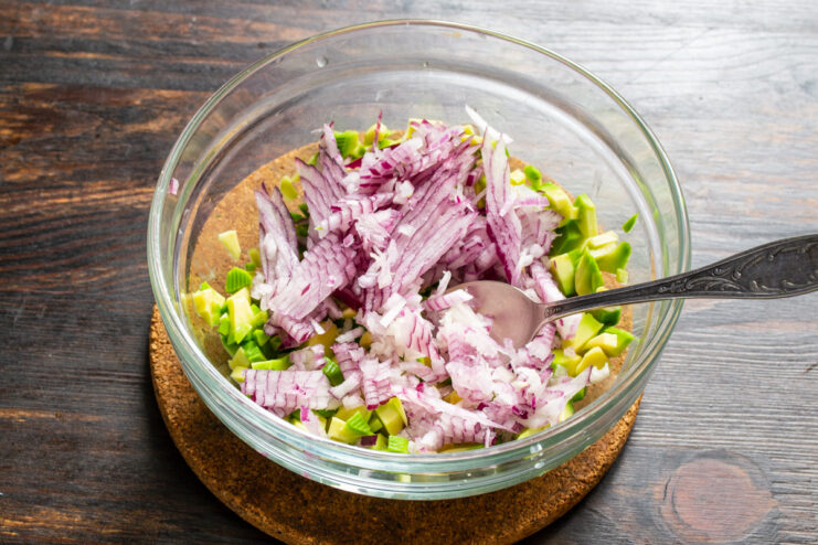 Adición de la cebolla morada Cebolla morada finamente picada en el tazón con aguacate