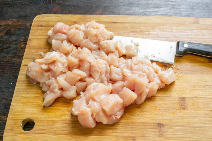 Preparando la pechuga Filete de pechuga de pollo cortado en cubos sobre una tabla