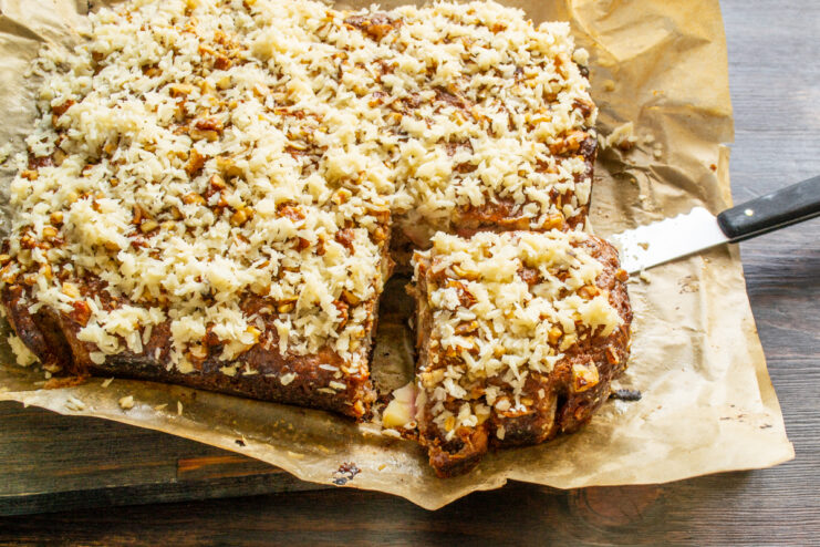 Pastel de manzana con coco cortado en porciones sobre papel pergamino