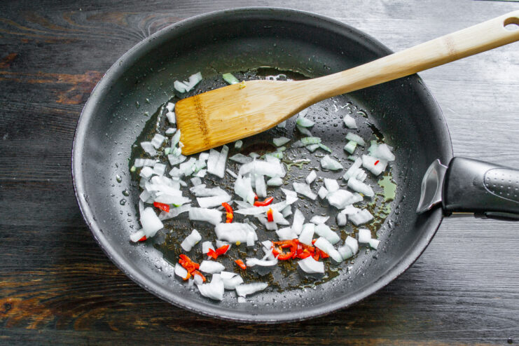 Sofrito de cebolla y chile Trozos de cebolla y aros de chile rojo picante sofriéndose en una sartén