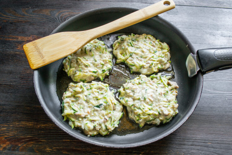 Tortitas de zucchini friéndose en aceite caliente