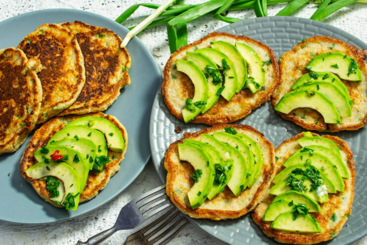 Panqueques de avena cubiertos con rebanadas de aguacate y cebollín fresco