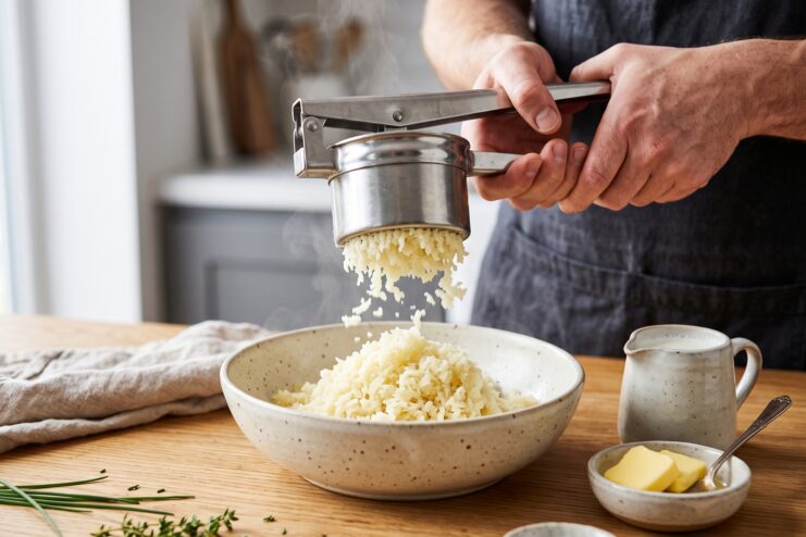 Preparación de puré de papa con prensapapas manual Proceso de elaboración de puré usando un prensapapas sobre un tazón profundo
