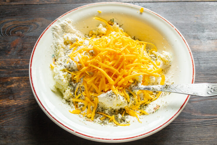 Integración del queso rallado Queso cheddar rallado sobre la mezcla de ingredientes