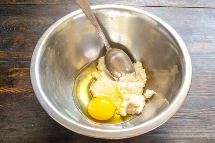 Mezcla de ingredientes líquidos Tazón de metal con queso fresco, huevo y aceite vegetal