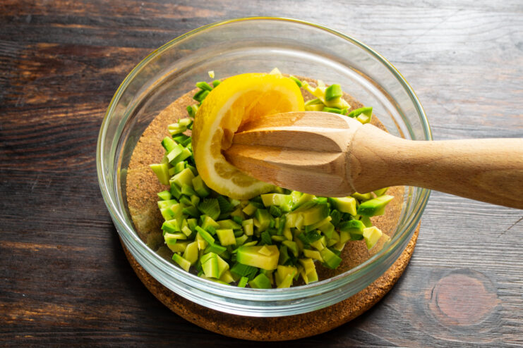 Adición del jugo de limón Exprimiendo jugo de limón sobre el aguacate picado