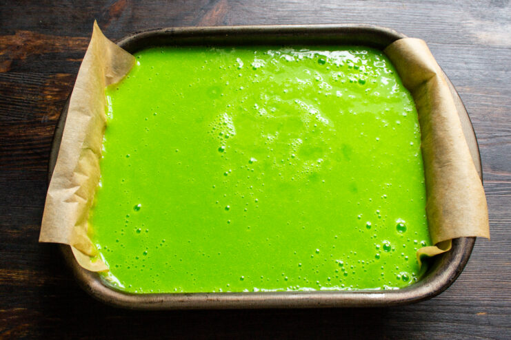 Reposo de la mezcla en el molde Mezcla verde de manzana en un molde rectangular forrado con papel para hornear.